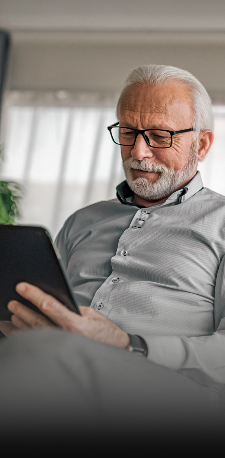 Un homme en chemise grise avec une tablette à la main.