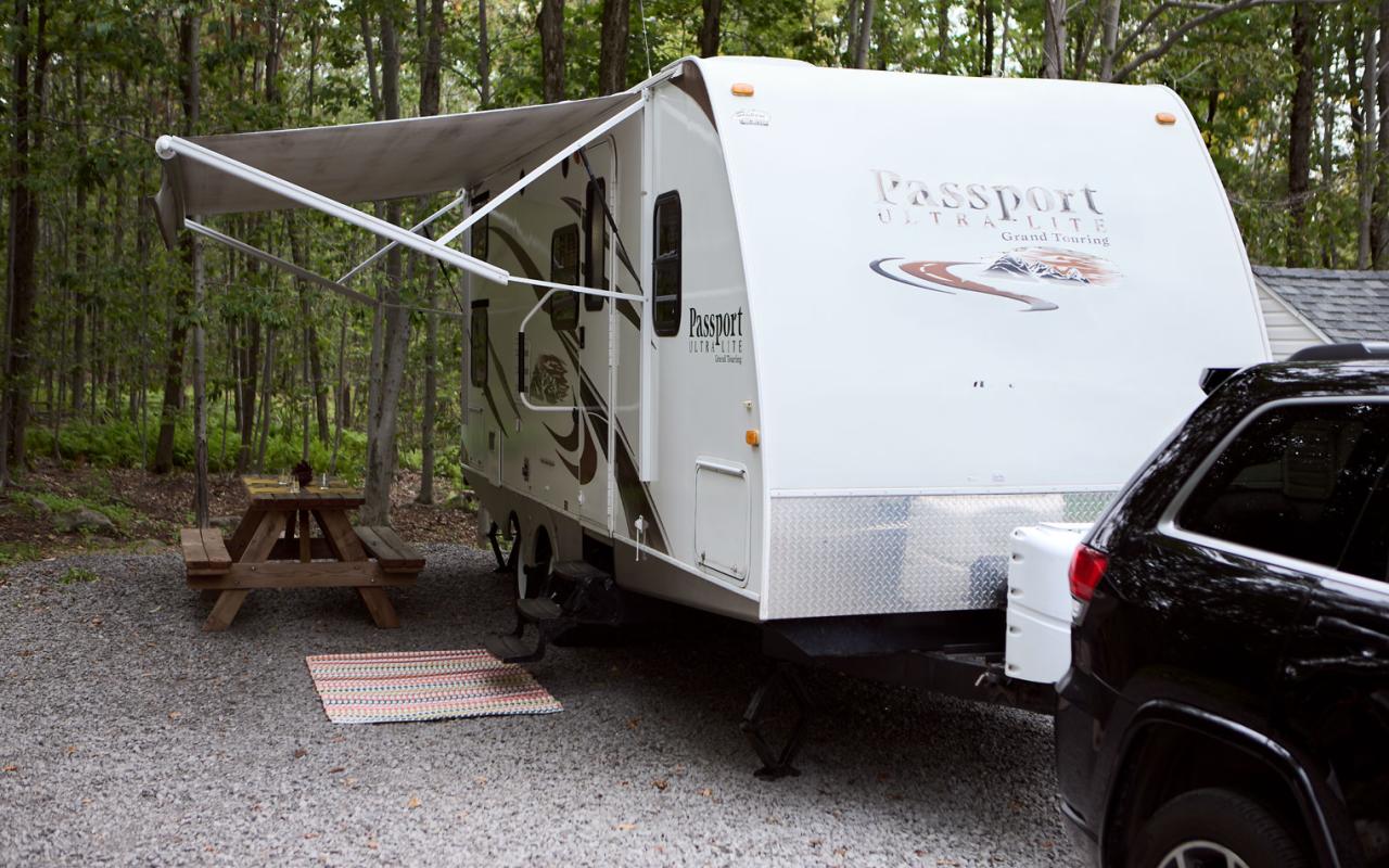 Une caravane devant le bois avec un auvent déployé