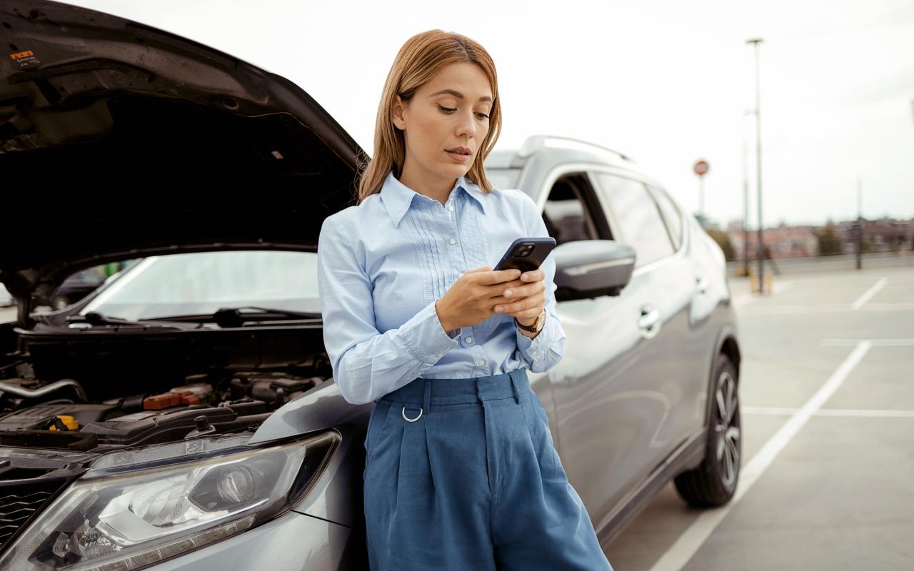 women on her phone next to a car