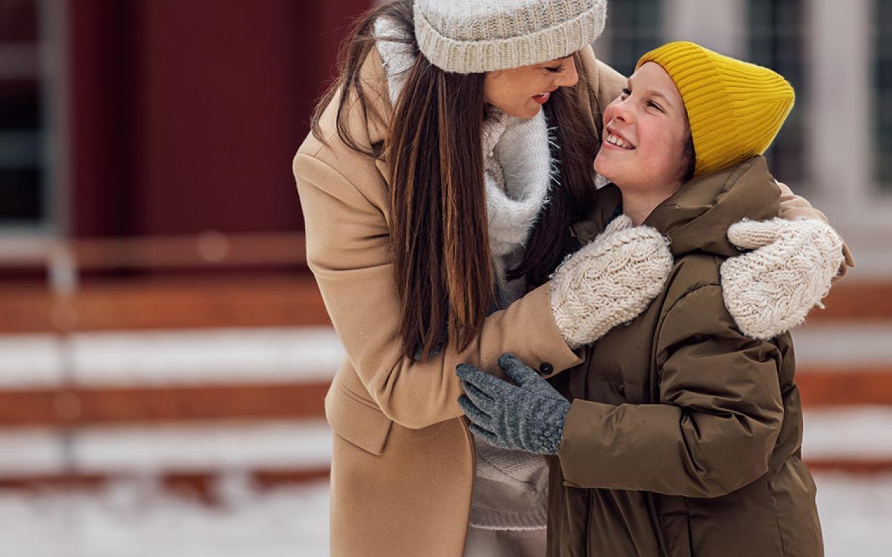 Parent et enfant devant une maison en hiver