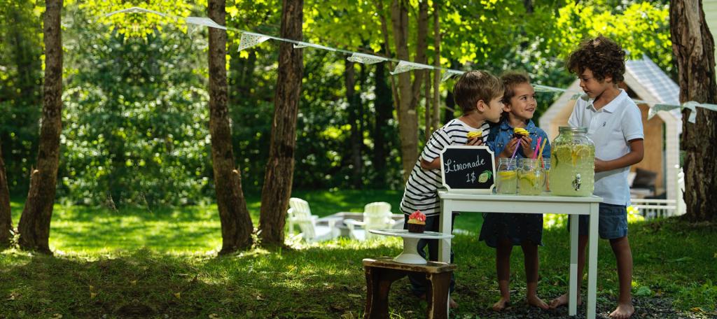 Des enfants vendent de la limonade dans un jardin