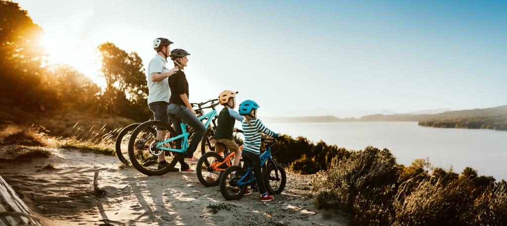 Famille à vélo avec enfants, vue sur un lac au coucher du soleil