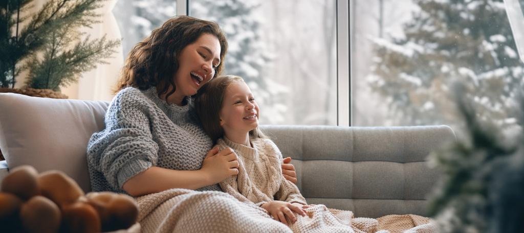 Personne adulte et enfant dans un salon avec vue sur un paysage hivernal