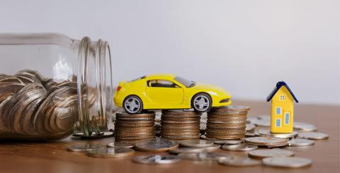 Voiture et maison en jouets sur des pièces de monnaie