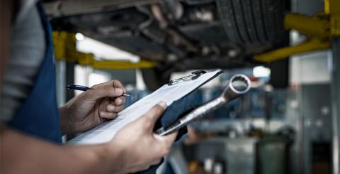 Mécanicien en train de faire l'inspection d'un automobile suspendue au garage