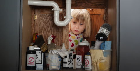 Enfant qui regarde des produits nettoyants chimiques sous un lavabo
