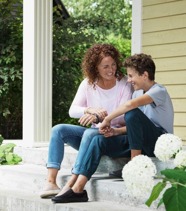 Une mère et son fils rient devant leur maison