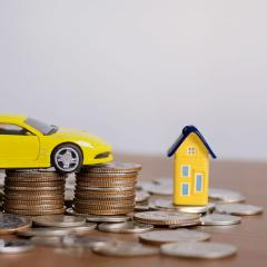 Voiture et maison en jouets sur des pièces de monnaie