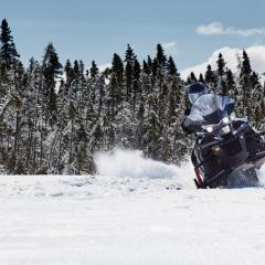 Motoneigiste en pleine manoeuvre de tournant dans la forêt enneigée