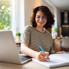 Jeunes étudiantes écrivant dans son cahier en consultant son ordinateur portable