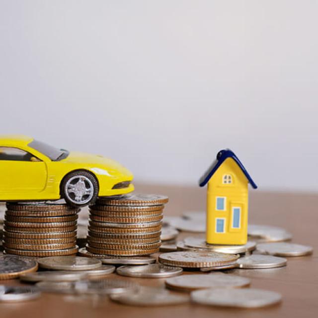 Voiture et maison en jouets sur des pièces de monnaie