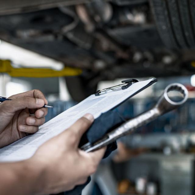 Mécanicien en train de faire l'inspection d'un automobile suspendue au garage