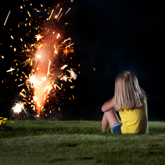 Jeune fille regardant un feux d'artifice familial dans sa cour.