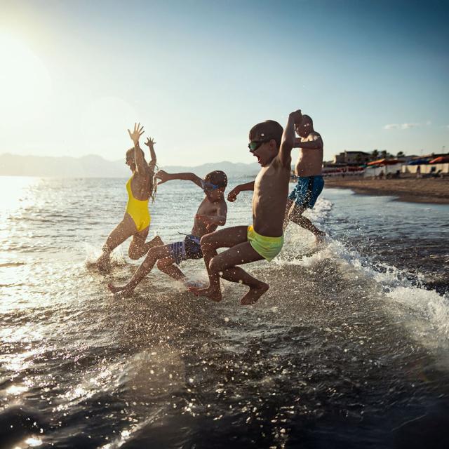 Famille se projetant dans l'eau à la plage