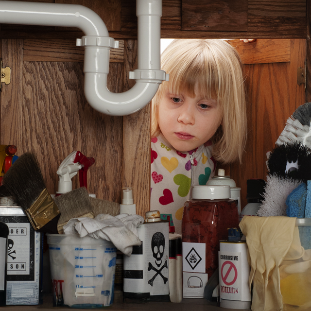 Enfant qui regarde des produits nettoyants chimiques sous un lavabo